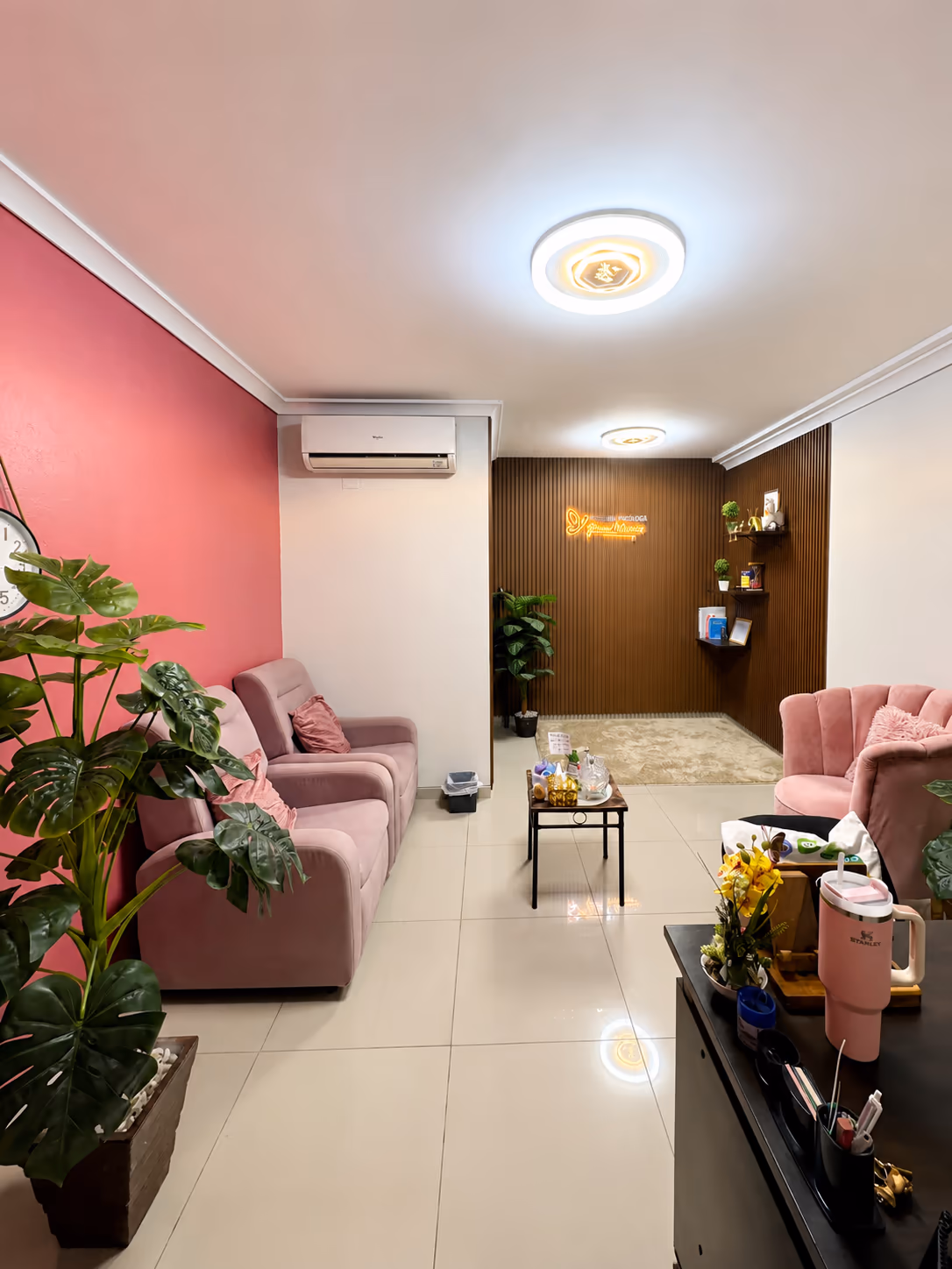 Sala principal del consultorio de Junisse Montaño en Santa Cruz de la Sierra, con sillones rosados y el letrero «Sanando» al fondo